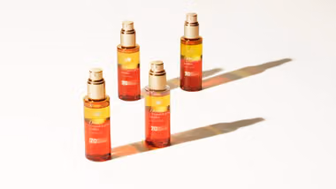 Four bottles of Dove’s UV Repair & Glow bi-phase serum to protect hair from UV damage. Glass bottles with orange and yellow serum.