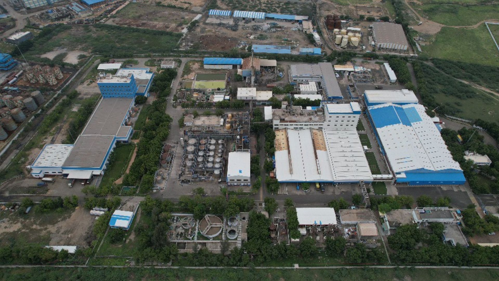 An aerial view of Unilever's Gandhidham factory in India. Blue, grey and white rooftops surrounded by green fields.