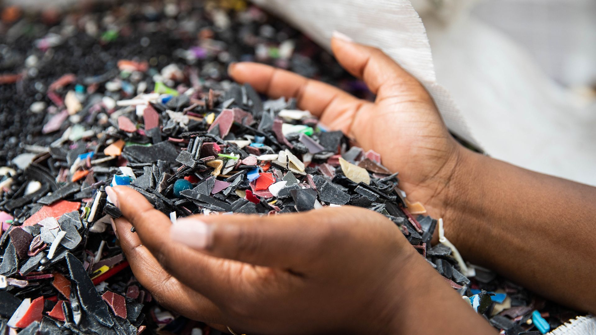 A pair of hands scooping up pieces of plastic from a bigger pile. In the top-right, the logos for Sunlight and Mr Green Africa are shown.