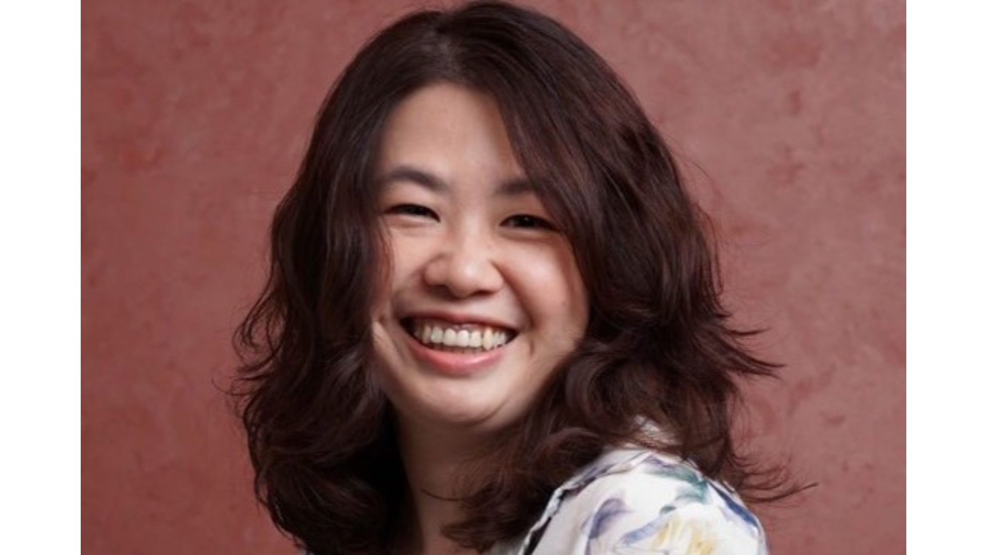 A photo of Unilever microbiome scientist Cheri Chu. Cheri has dark shoulder-length hair and is smiling into the camera. 
