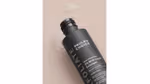 A bottle of Paula’s Choice Liquid Exfoliant lying on its side with drops of the product visible.