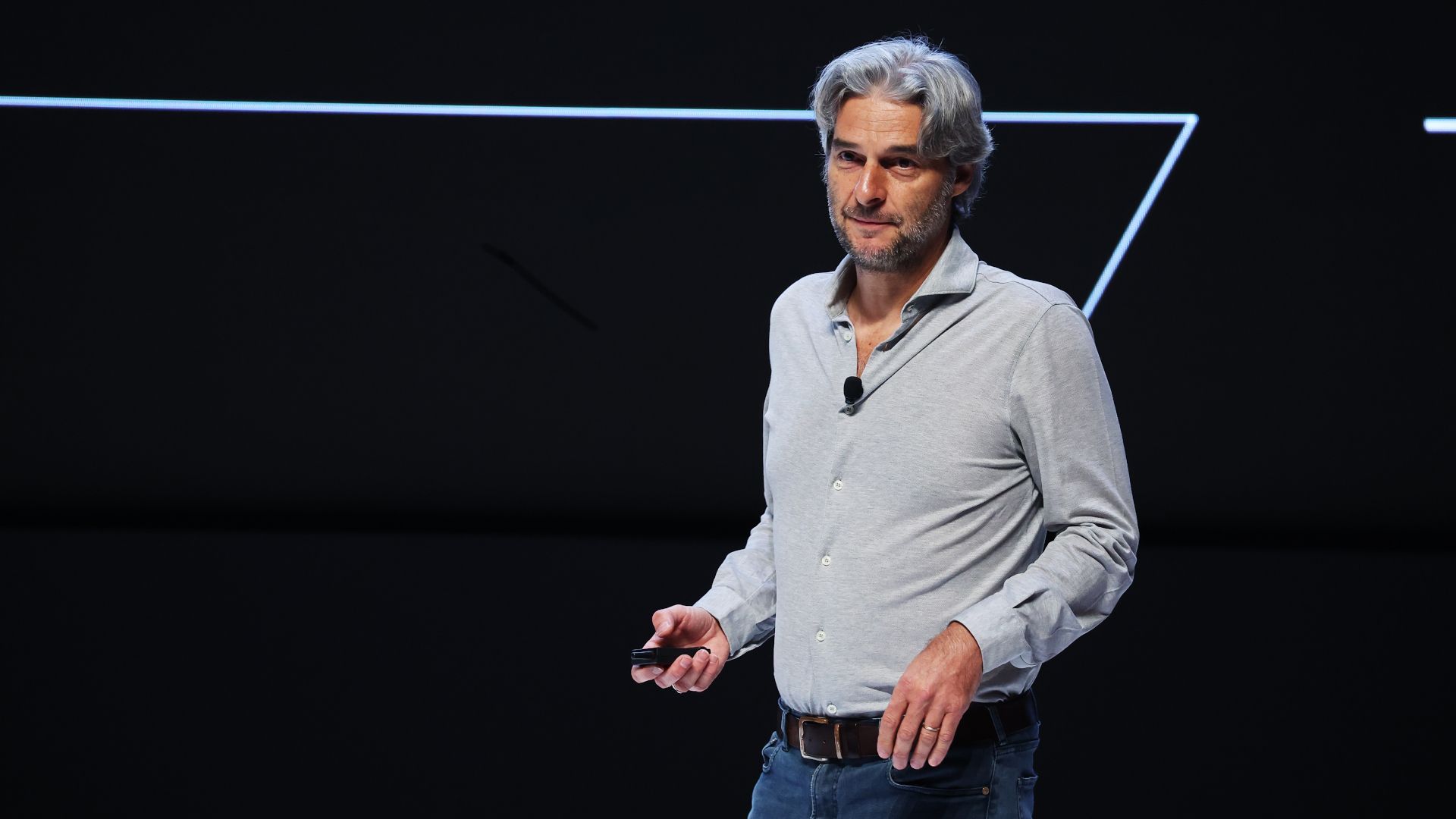 Alessandro Manfredi in jeans and a white shirt speaking on stage