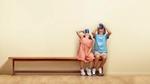 Boy and girl sitting on a bench with their heads thrown back to get every last drop of Horlicks from their cup