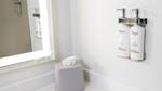 Bottles of Dove shampoo, conditioner and body wash in silver pump dispensers on a white tiled bathroom wall.