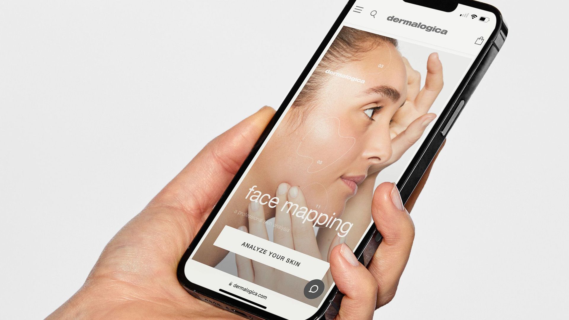 Hand holding mobile phone showing screenshot of Dermalogica’s face mapping app.