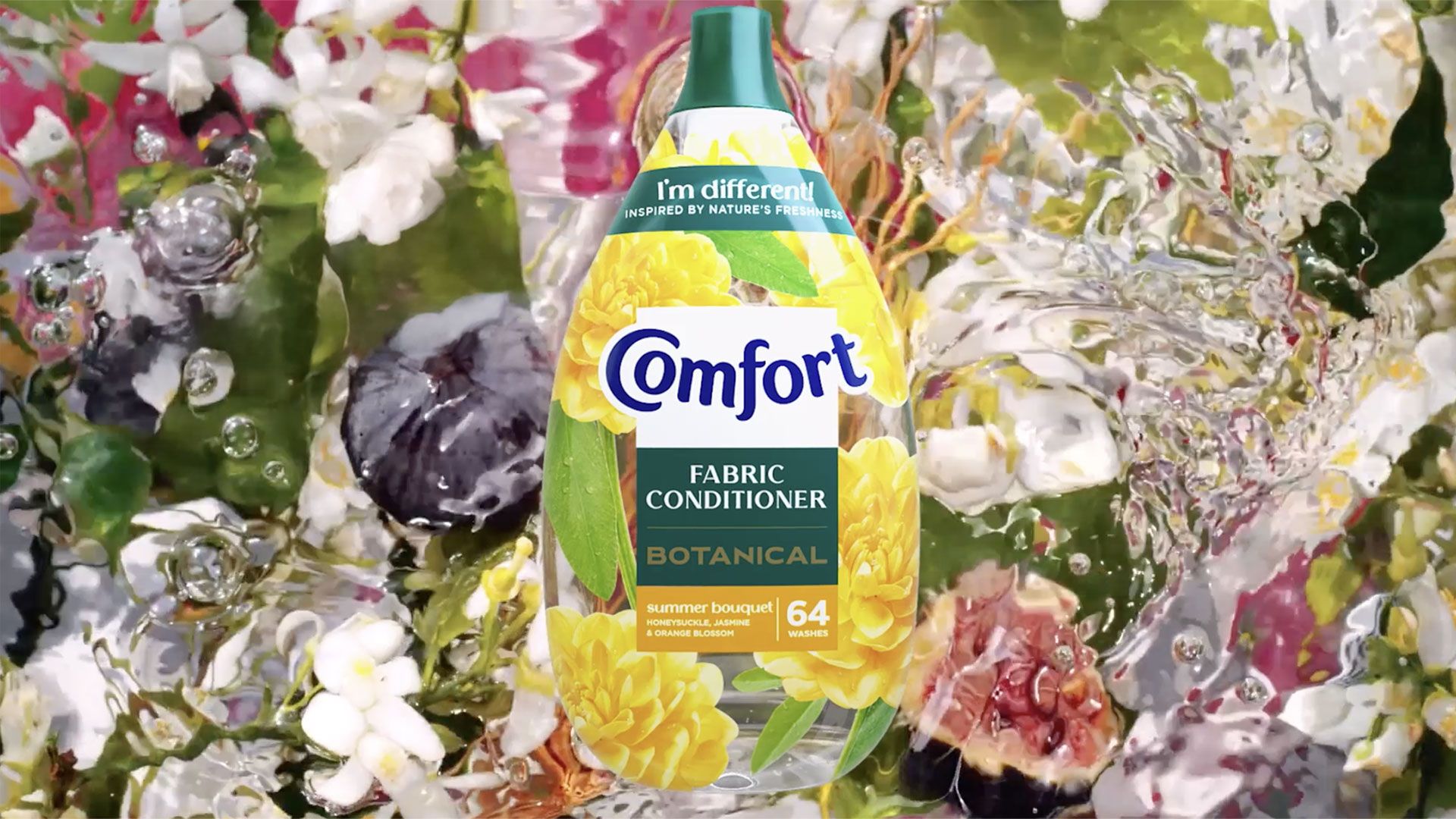 A bottle of Comfort Botanical fabric conditioner appears over a vivid, watery background filled with brightly coloured flowers and petals. The bottle has a green cap and a floral design featuring yellow blooms. Beneath it, water ripples and reflections blend the colours of pink, white, and yellow flowers, creating a fresh, nature-inspired setting.