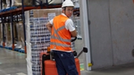 Worker in overalls and hard hat pulling a trolley across a factory floor