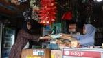 Two women in hijabs smiling at each other in a shop whilst one passes the other a bottle of product.