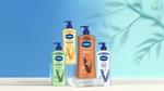 Four Vaseline Intensive Care lotions, including ‘Soothing Hydration’, ‘Nourishing Moisture’, ‘Cocoa Radiant’ and ‘Advanced Repair’. Each bottle is equipped with a pump dispenser. The products are arranged in front of a blue background, with a leaf motif.