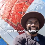 Elfried Samba wears a wide-brimmed hat standing in front of a large FIFA World Cup 2026™ football pop up.