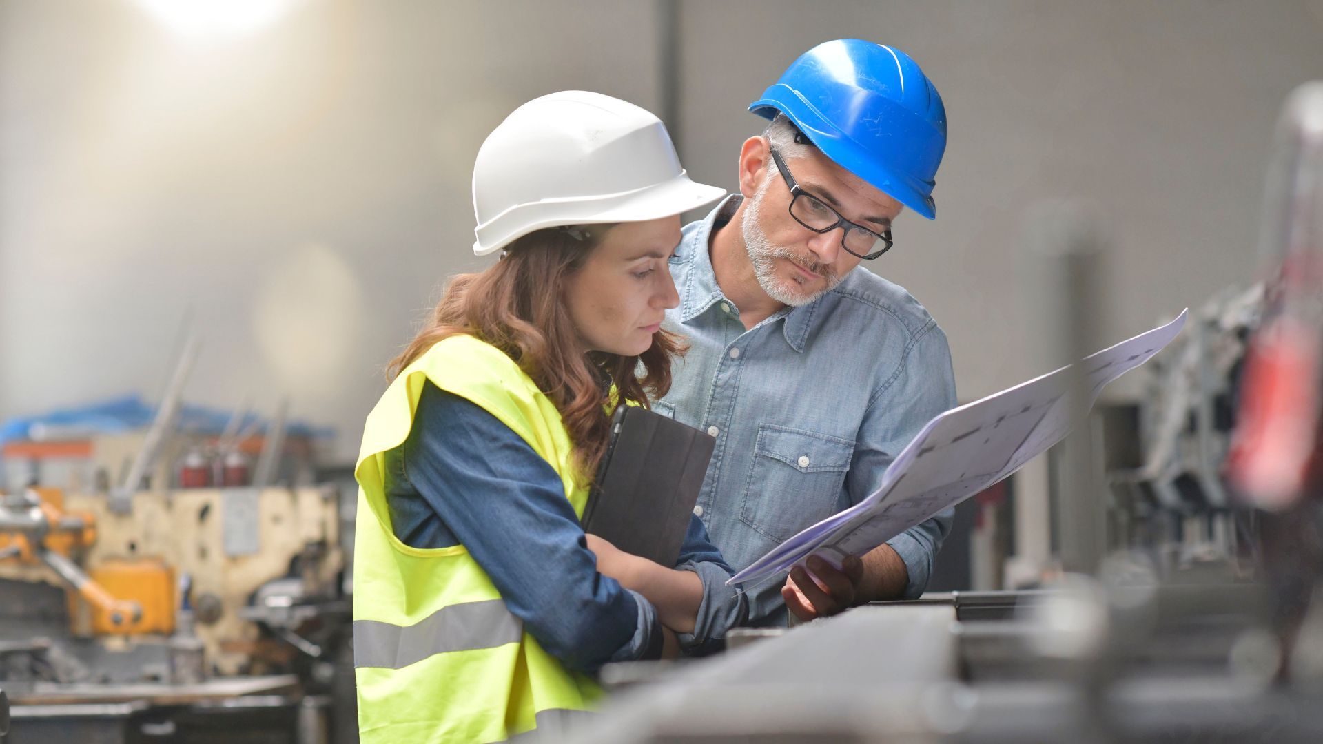 Two employees dressed in hard hats having a conversation in a factory