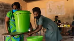 A green hand washing station is used by two women
