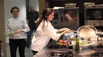 Women chef in industrial kitchen creating and serving a plant-based dish