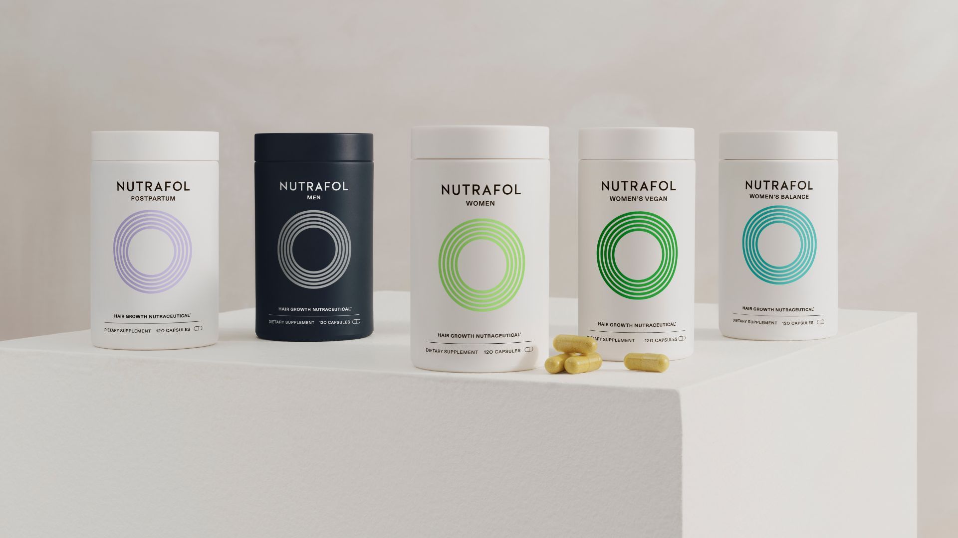 Five containers of Nutrafol hair growth supplements, in black and white jars, arranged in a row.