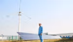 Worker in front of solar panels and wind turbine