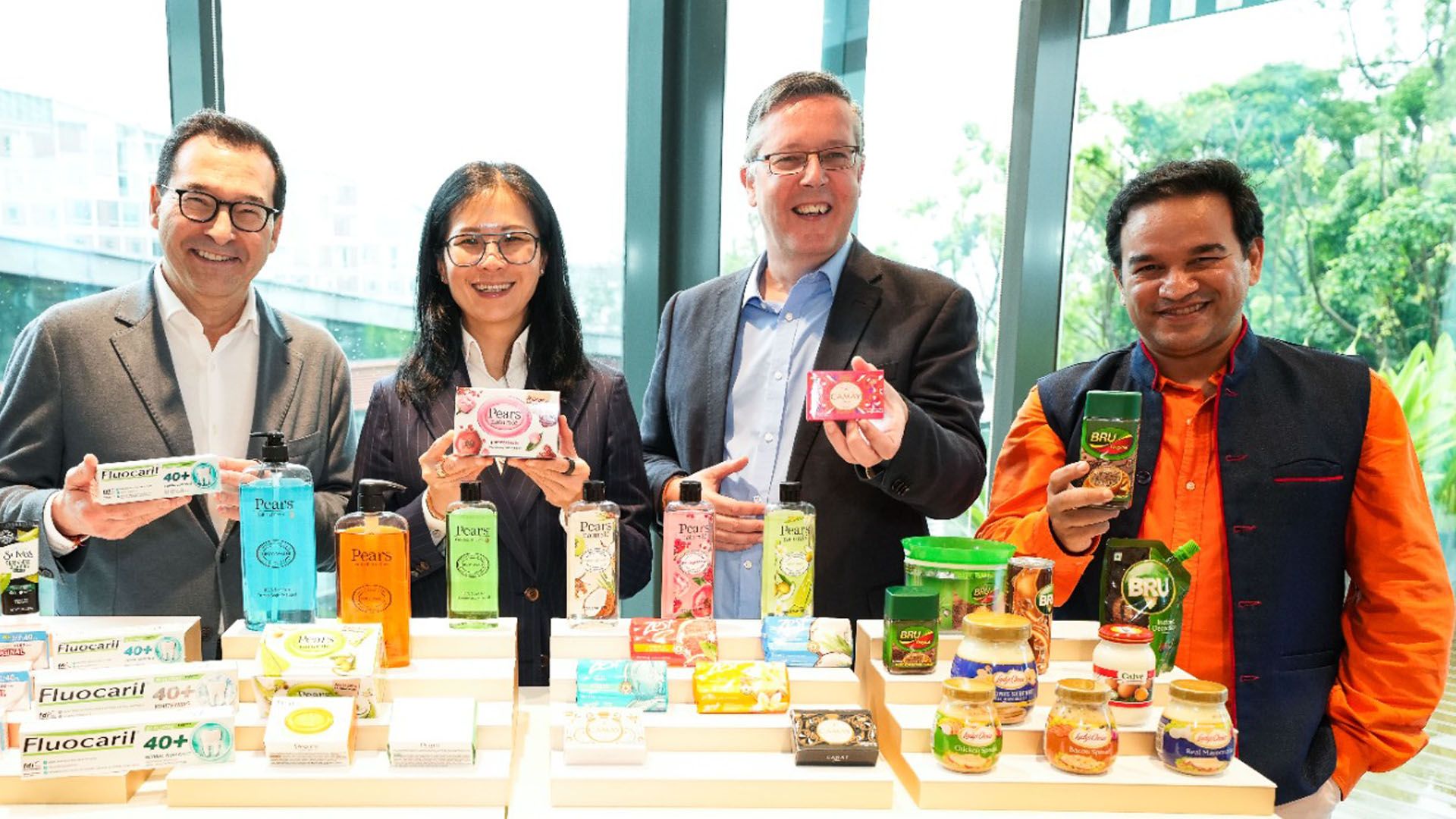 Unilever International CEO Aseem Puri with team members in front of a table of products including Pears soap and Bru coffee.