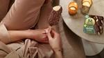 Woman sitting beside a table with a multi-pack of vegan Mini Magnums and holding a vegan Mini Magnum in her hand