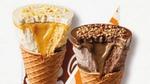 Cornetto Max’s Mango and Vanilla cone and Hazelnut and Chocolate cone sitting side by side. Both are partially unwrapped, and a bite has been taken out of each to show the thickness of each cone’s chocolatey disc top, sauces and ice cream.