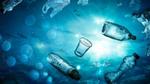 Underwater perspective of various plastic bottles, cups and shopping bags floating in the sea.