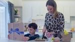 Mother and child in kitchen preparing a meal from a Hellmann’s recipe book.