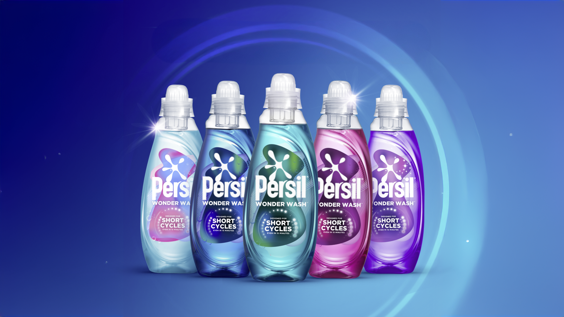 Five bottles of Persil Wonder Wash detergent in different colours arranged in a row against a blue background, with labels highlighting performance on short wash cycles.