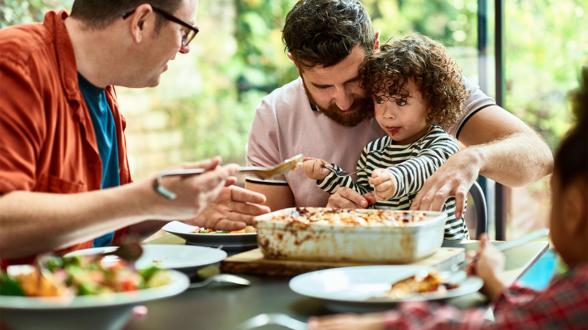 Young child with male guardians eating a plant-based meal