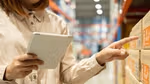 A person’s hand tapping their mobile phone screen to open an app and place a retail goods order