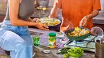 A man and a woman cooking and plating up a dish, with a Knorr Chicken Bouillon Powder jar on the counter.
