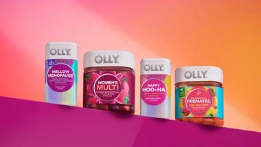 Four Olly vitamin products line up against a purple and peach background with a spotlight on them.