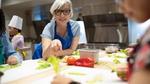 Woman in blue apron leaning over a kitchen counter
