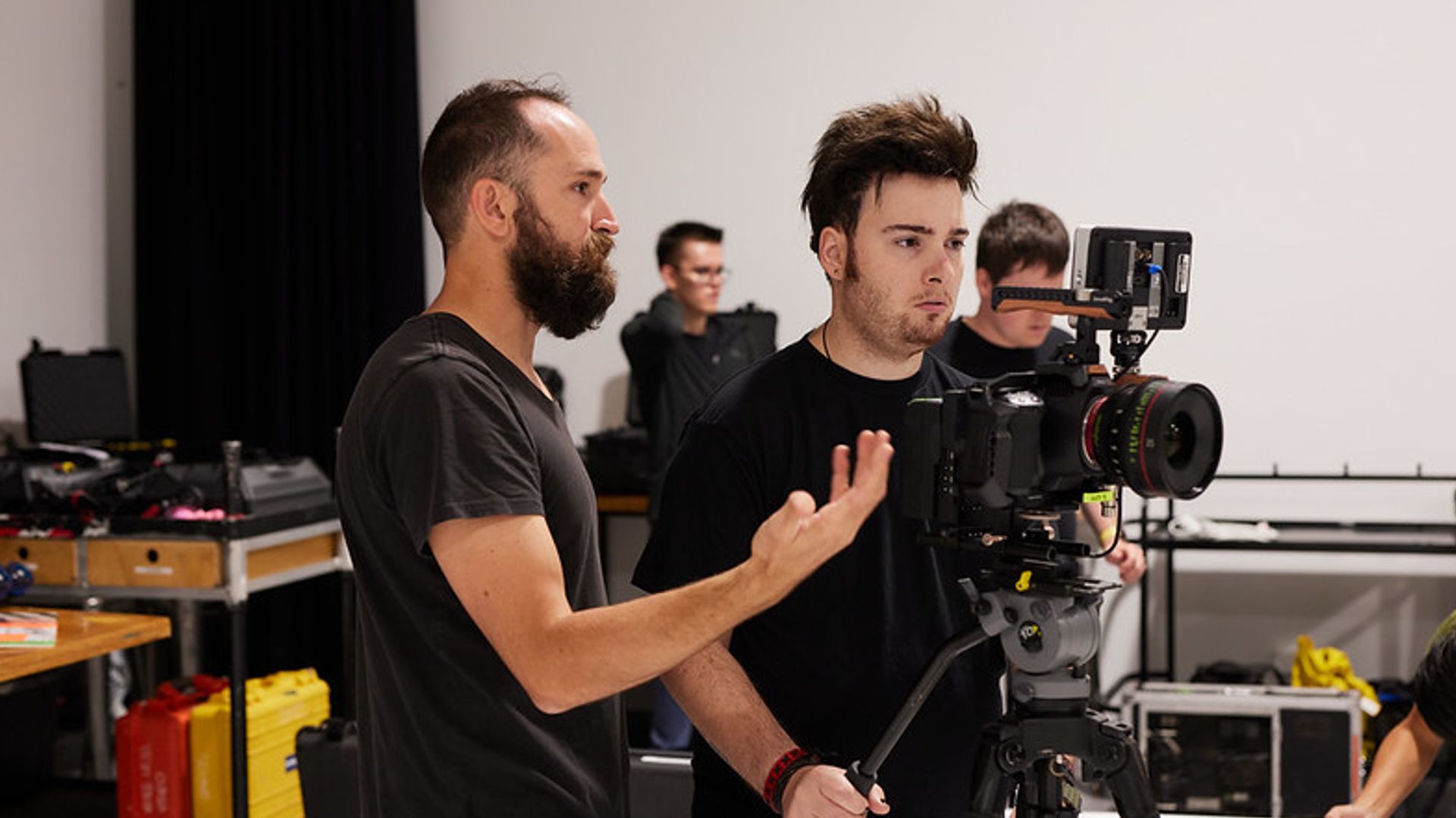 Camera operator in a production crew helping a fellow crew member with disabilities use the camera on set