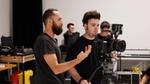 Camera operator in a production crew helping a fellow crew member with disabilities use the camera on set