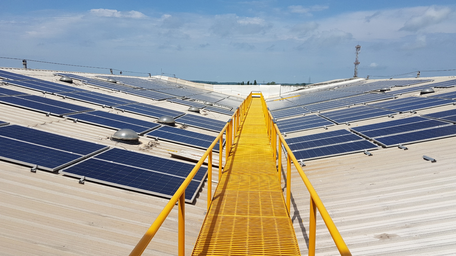 Yellow bridge on top of a building covered in solar panels 