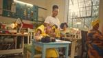 Three women working on sewing machines smile at a child learning to sew by hand