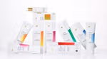 An arrangement of Dove cream serum from the Premium Body Care range. White tubes and bottles, each featuring colourful gradient labels, displayed upright and leaning against one another on a clean white background.