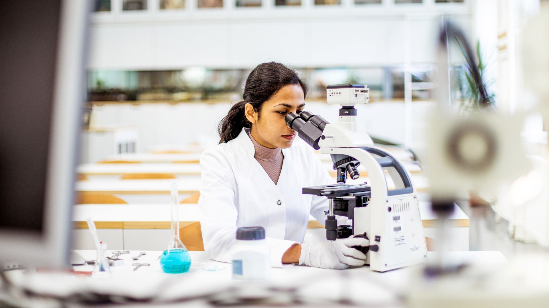 A woman in a laboratory using a microscope