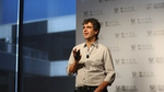 Fernando Fernandez standing on stage wearing a light-colored shirt and speaking in front of a backdrop featuring repeated “Beauty & Wellbeing” and Unilever logos, with a microphone clipped to the shirt.