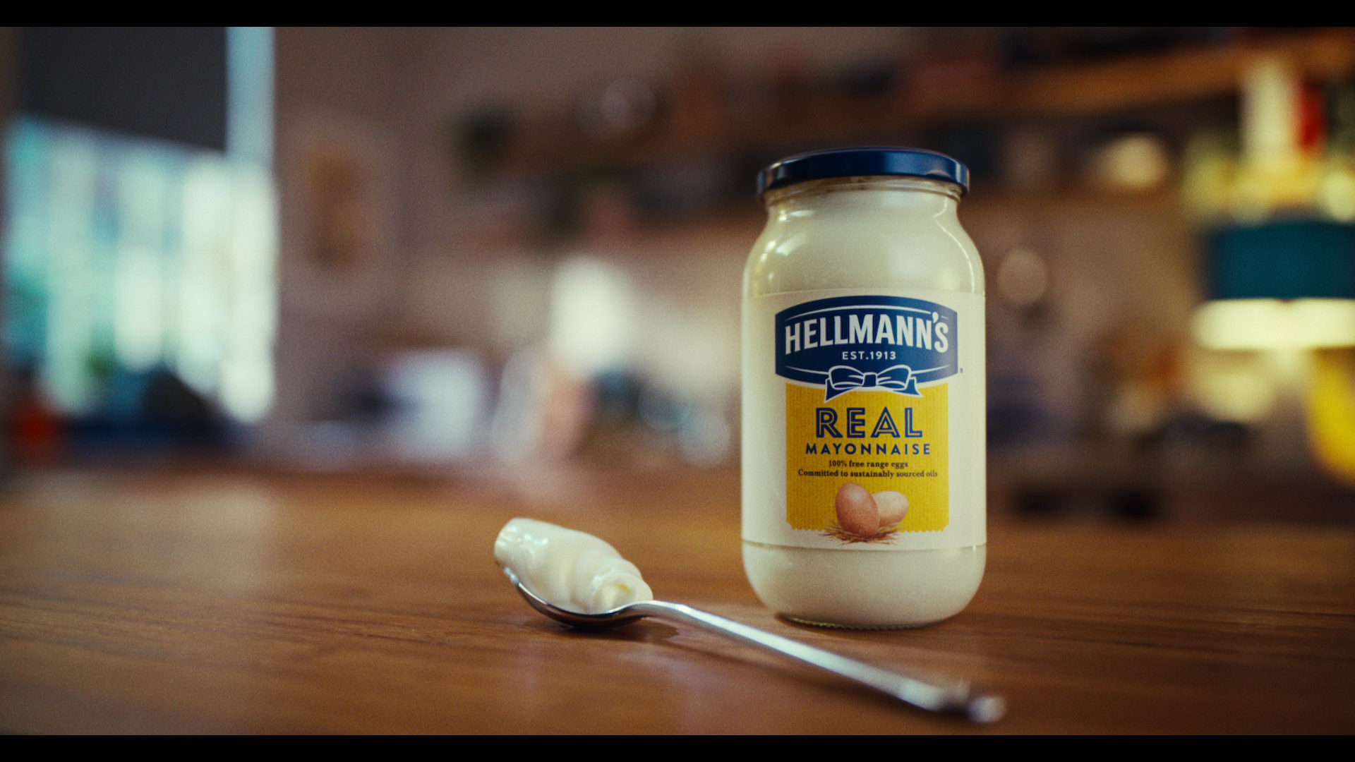 A jar of Hellmann’s mayonnaise with a spoon on a wooden table