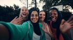 Vier multiculturele vrouwen glimlachen en zwaaien naar de camera