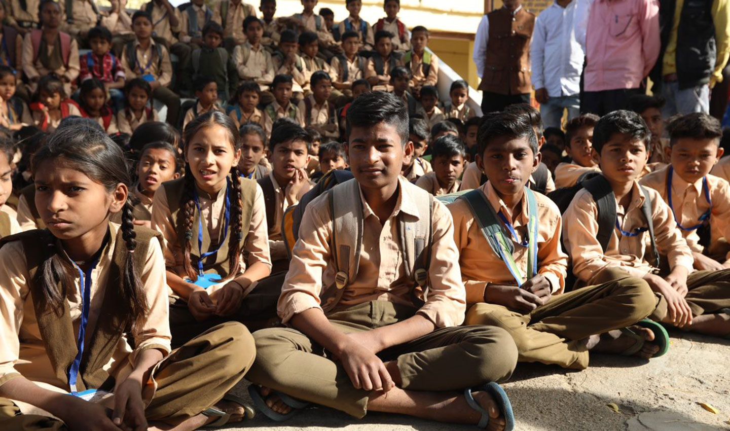 A group of schoolchildren sitting on the ground. Unilever works with UNICEF to improve sanitation in schools.