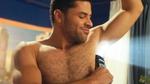 A man applies Axe deodorant to his underarms. A beam of light appears behind him.