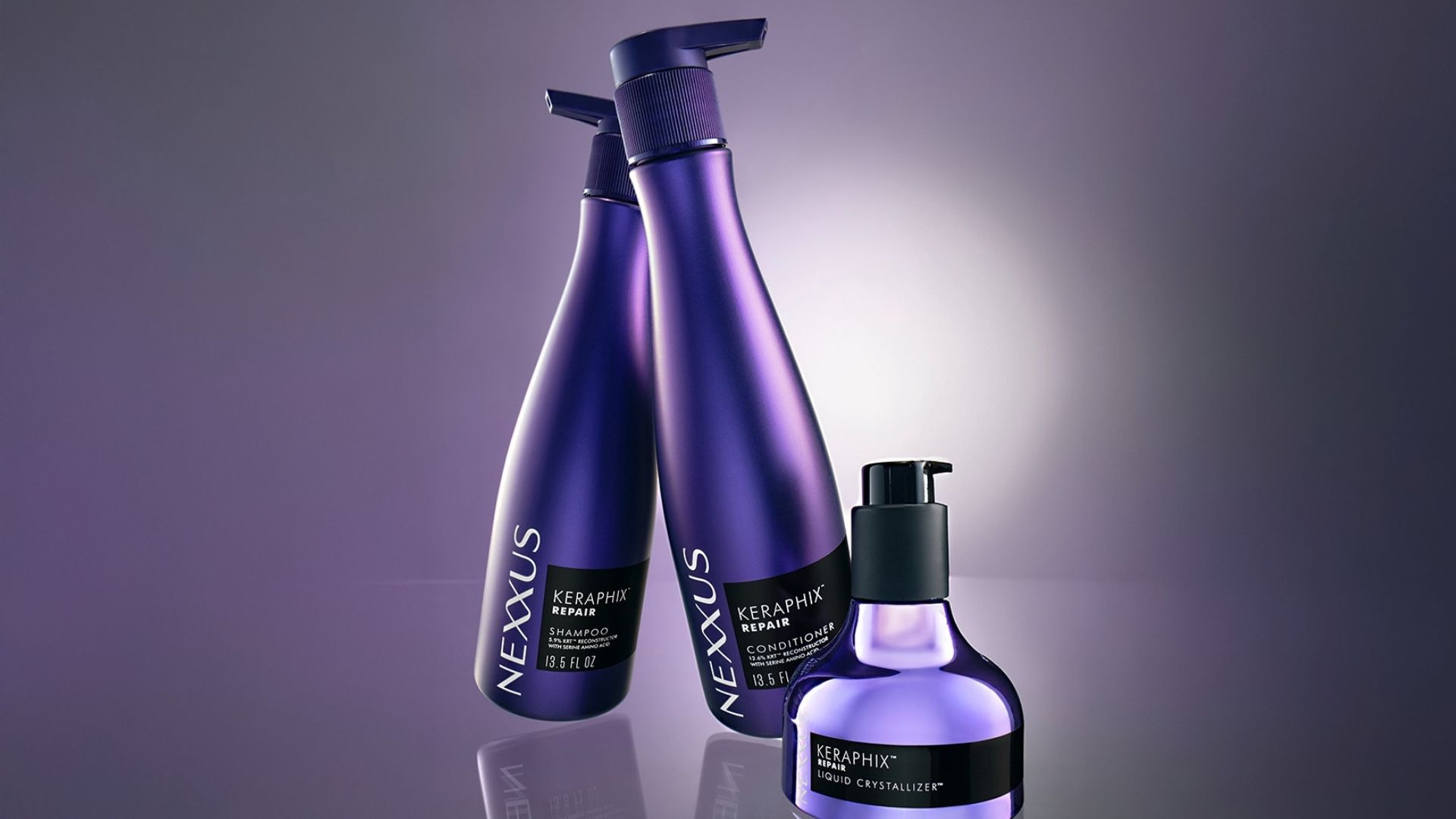 Three bottles of Nexxus Keraphix products. Lilac bottles of shampoo and conditioner, and a smaller metallic bottle with black pump.