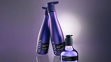 Three bottles of Nexxus Keraphix products. Lilac bottles of shampoo and conditioner, and a smaller metallic bottle with black pump.