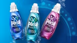 Three Persil Wonder Wash bottles in blue, teal and pink variants on a blue background with water splash effects.