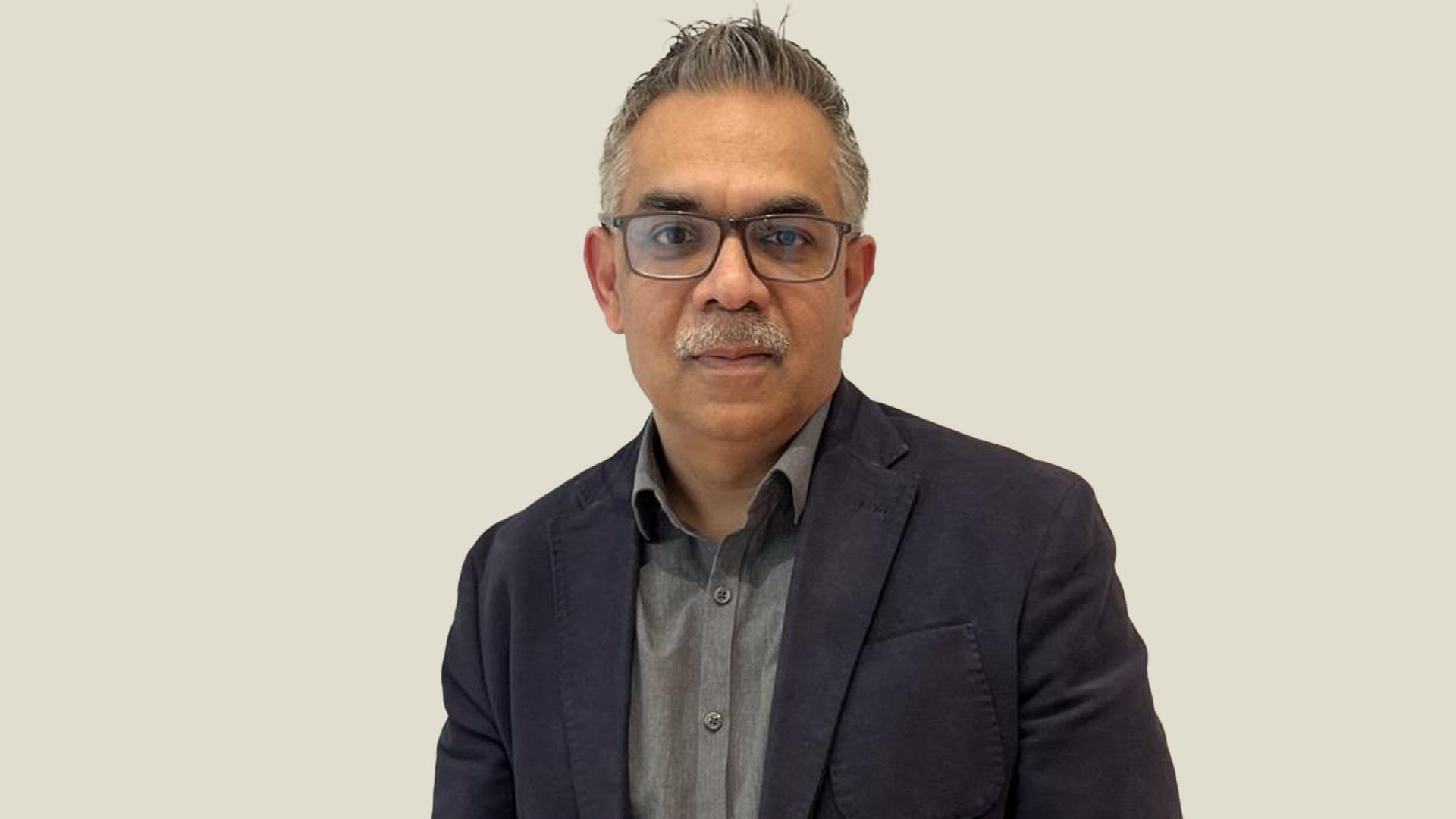 Portrait of Vivek Sirohi, a man with grey hair and moustache wearing glasses.