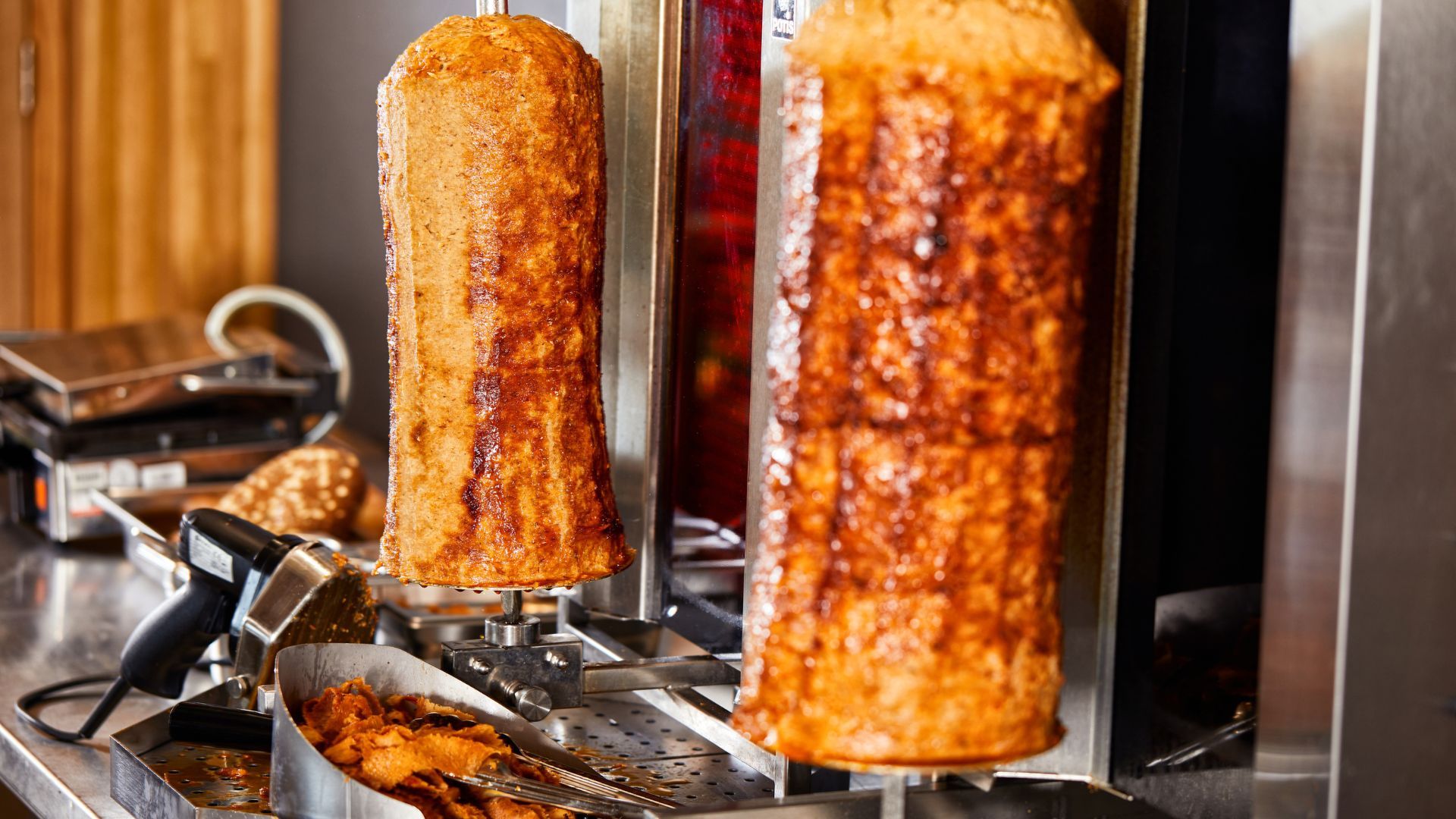 Two plant-based kebabs cooking on a rotating spit