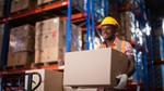 Man smiling and carrying a box in a warehouse
