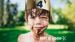 Young boy smiling, splashed in mud, wearing a gold paper crown.