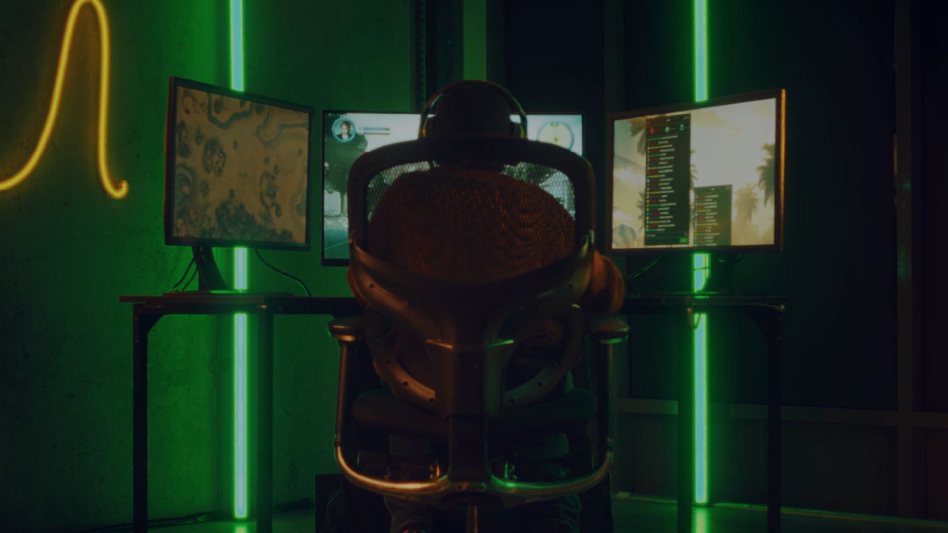 A gamer sits in front of three gaming screens.