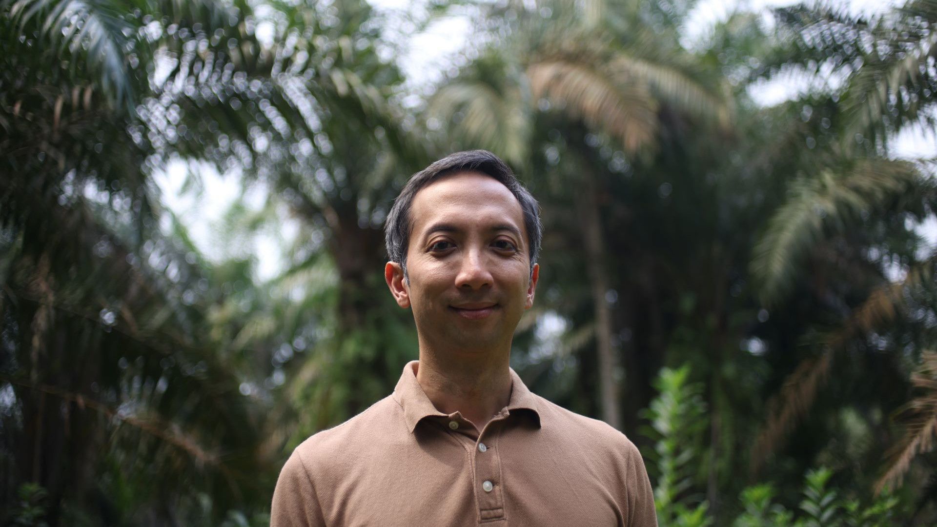 Rauf Prasodjo, Senior Manager for Sustainable Sourcing at Unilever in a palm-oil forest looking front on wearing a brown t-shirt.
